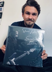 a man holding up a picture of a man holding a guitar